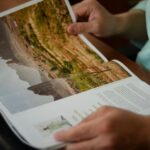 Close-up of a man reading a magazine indoors, focusing on hands and pages.